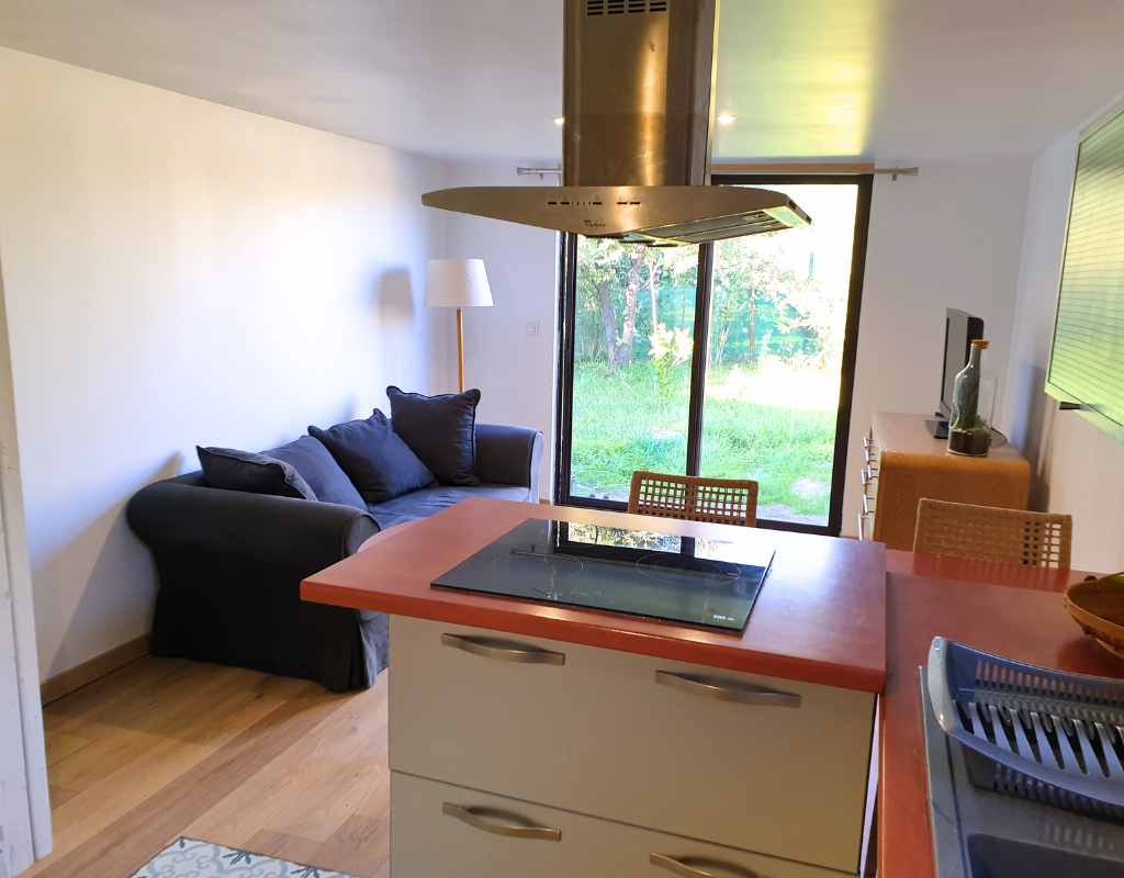 Vu depuis la cuisine vers le salon. L'entrée, le salon et le début de la cuisine sont montrés. Casa Pinya met en avant le style moderne et simple de la maison Bambù.